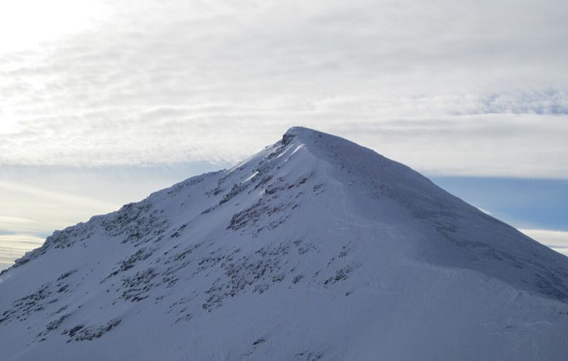 A snow-covered glacier summit under a clear sky