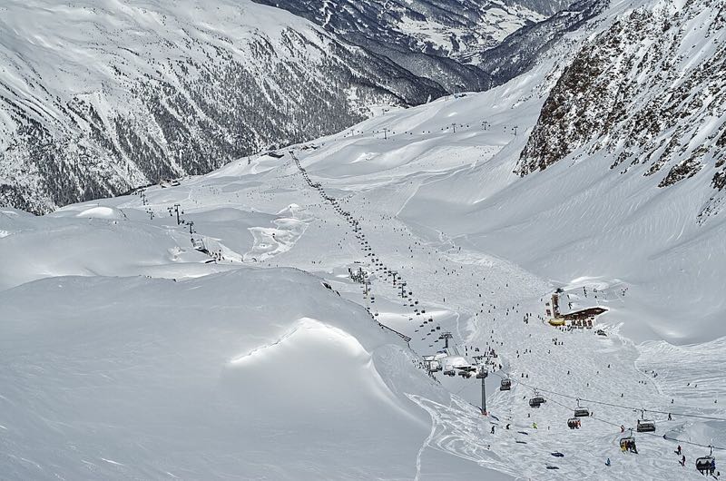 Sweeping snow-covered ski slopes of Obergurgl-Hochgurgl dotted with skiers and chairlifts amid high peaks