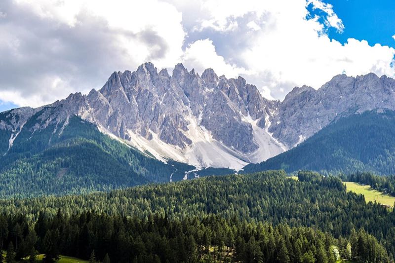 Dramatic jagged Dolomite spires rising above green forest near Cortina d Ampezzo