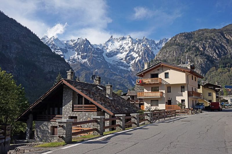 A stone and timber street in Courmayeur with snow-capped peaks behind