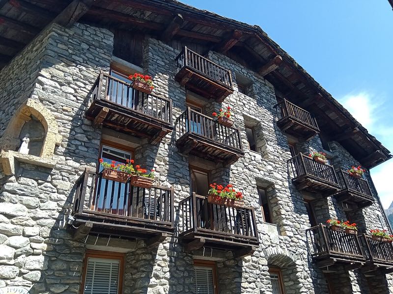 Stone houses with wooden balconies and flowers in the hamlet of Dolonne