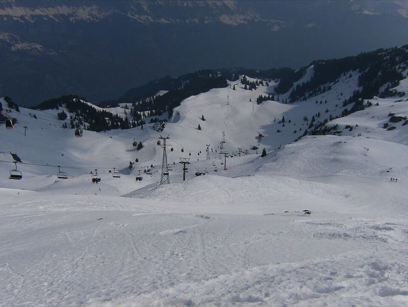 Wide open pistes crossed by chairlift lines on a snowy slope