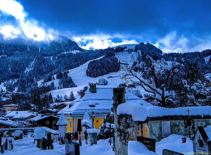 Snow-covered Kitzbühel with the Hahnenkamm and the Streif ski piste behind at dusk