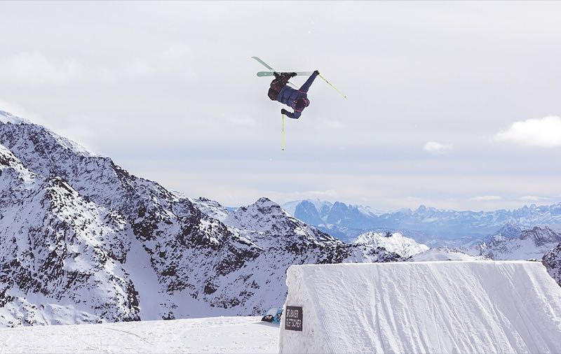 Freestyle skier launching off a Stubaier Gletscher kicker with a backdrop of snow-covered peaks
