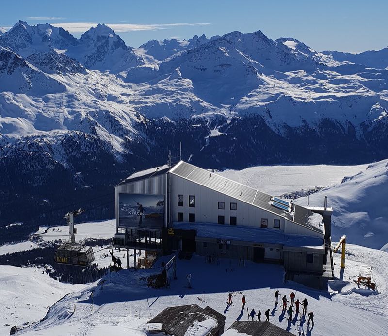 A mountain-top lift station in deep snow with the Engadin beyond